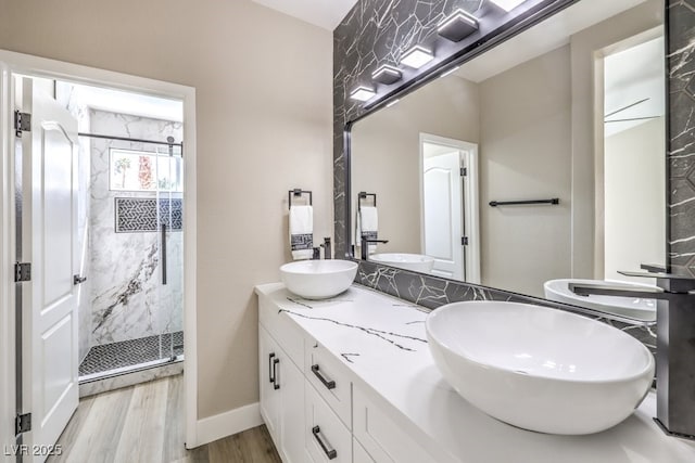 full bathroom featuring a marble finish shower, a sink, and double vanity