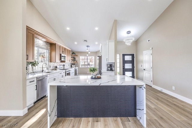 kitchen featuring open shelves, light wood-style flooring, a sink, and appliances with stainless steel finishes