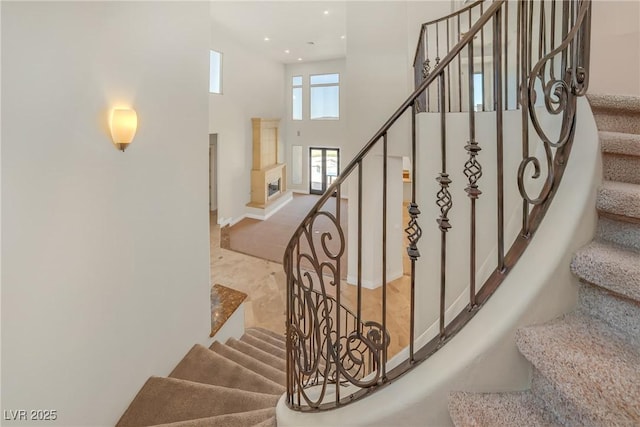 staircase with recessed lighting, baseboards, and a high ceiling