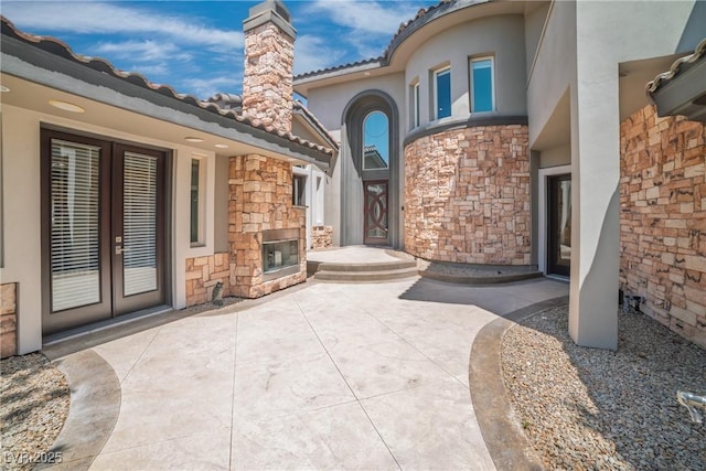 view of patio / terrace featuring an outdoor stone fireplace and french doors