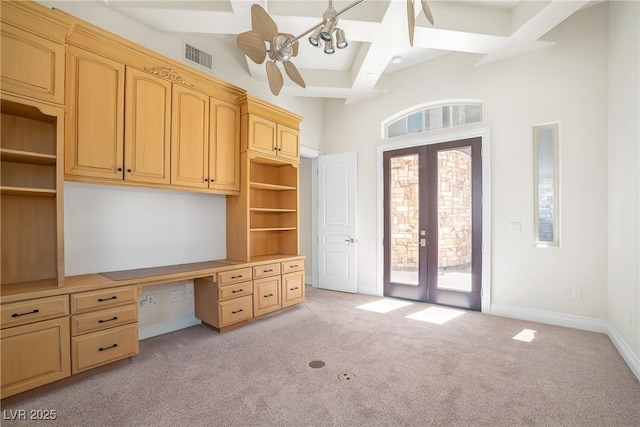 unfurnished office with built in desk, light colored carpet, coffered ceiling, beam ceiling, and french doors