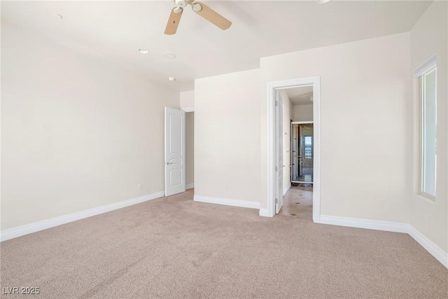 unfurnished bedroom featuring light colored carpet, a ceiling fan, and baseboards
