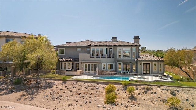 back of property with a chimney, french doors, a fenced backyard, and a tile roof