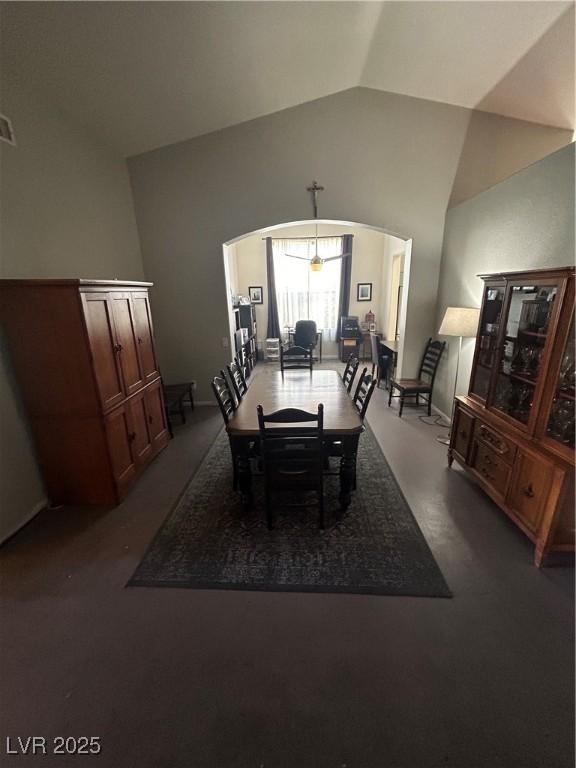dining room featuring arched walkways, dark colored carpet, and high vaulted ceiling