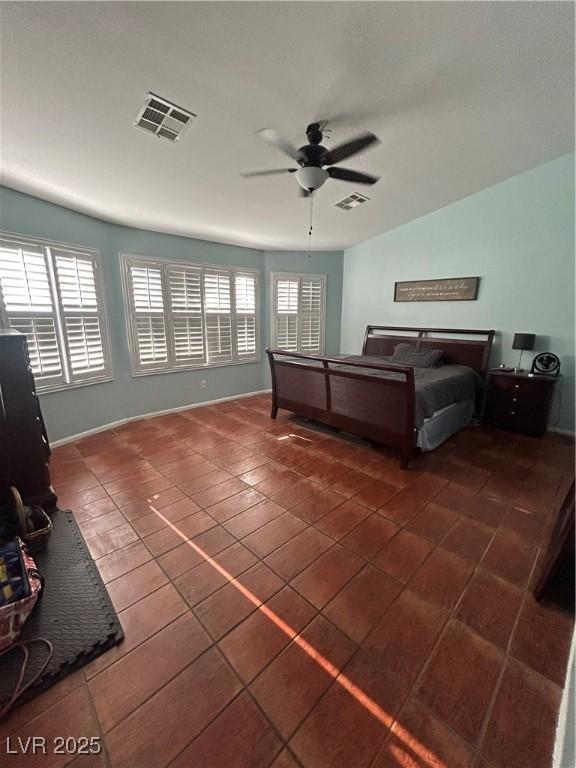 tiled bedroom featuring multiple windows, ceiling fan, and baseboards