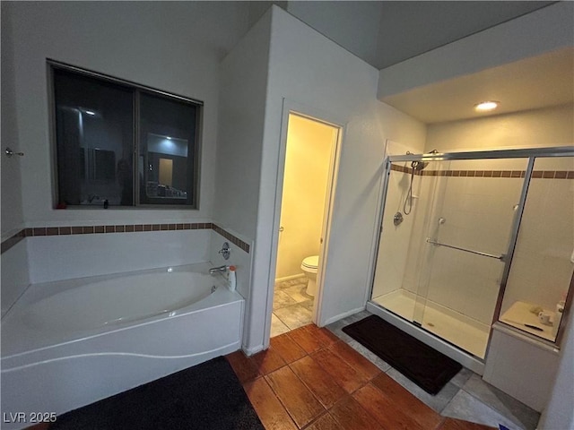 bathroom featuring a shower stall, toilet, and a garden tub