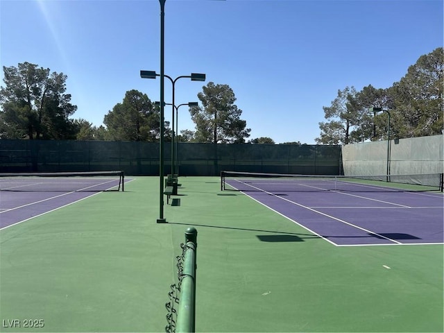 view of tennis court with community basketball court and fence