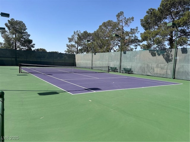 view of tennis court with community basketball court and fence