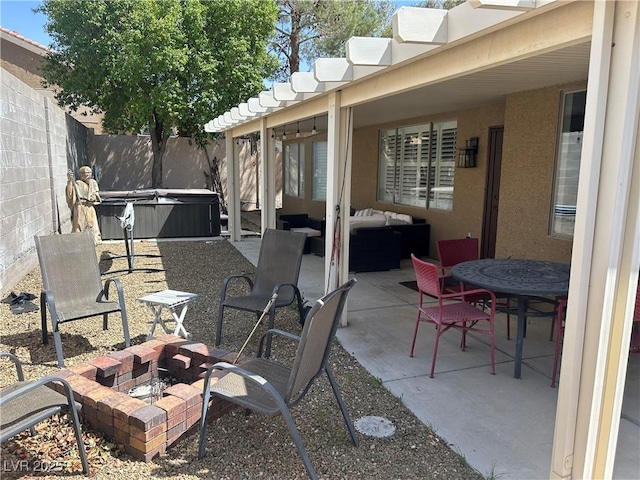 view of patio with a hot tub, a fenced backyard, and a fire pit