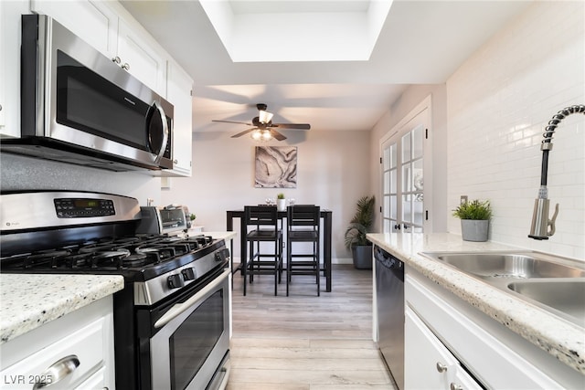 3120 S Eastern Ave Unit 6, Las Vegas, NV 89169 - kitchen with white cabinets, appliances with stainless steel finishes, a sink, and light wood-style floors