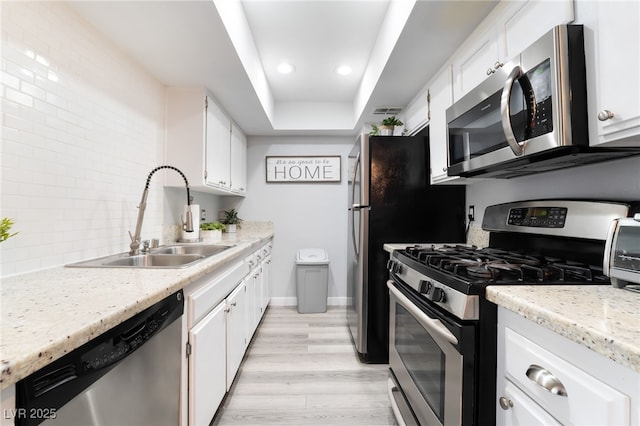 3120 S Eastern Ave Unit 6, Las Vegas, NV 89169 - kitchen with appliances with stainless steel finishes, tasteful backsplash, a sink, a raised ceiling, and white cabinets
