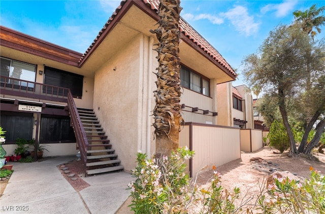 3120 S Eastern Ave Unit 6, Las Vegas, NV 89169 - view of side of home featuring stucco siding, a tile roof, stairway, and fence