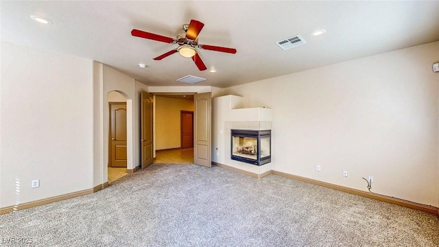 524 Blanche Ct, Henderson, NV 89052 - unfurnished living room with visible vents, a ceiling fan, light carpet, and a multi sided fireplace