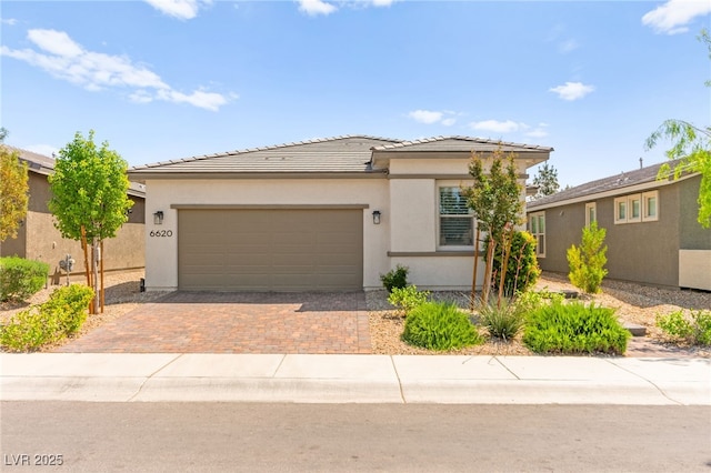 view of front of house with an attached garage, a tile roof, stucco siding, and decorative driveway
