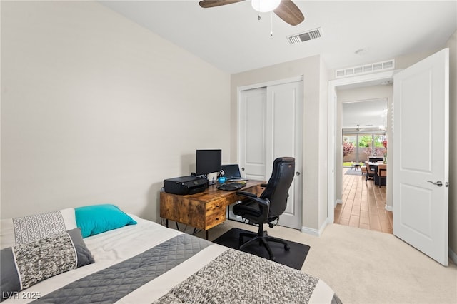 carpeted bedroom featuring a closet, visible vents, baseboards, and ceiling fan
