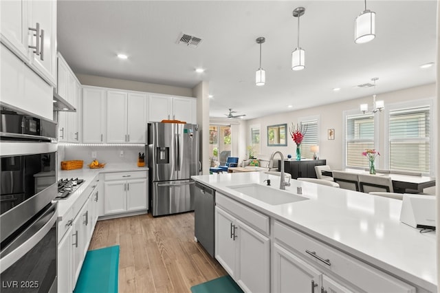 kitchen featuring white cabinets, visible vents, stainless steel appliances, and a sink