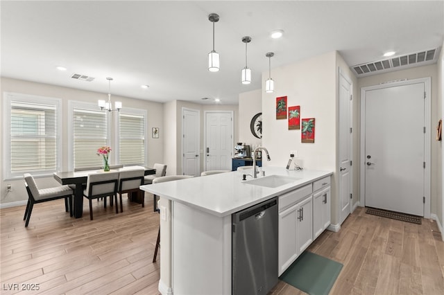 kitchen with stainless steel dishwasher, a sink, light wood-type flooring, visible vents, and a chandelier