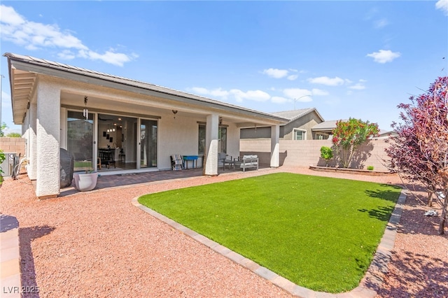 back of property with stucco siding, fence, a patio area, and a lawn