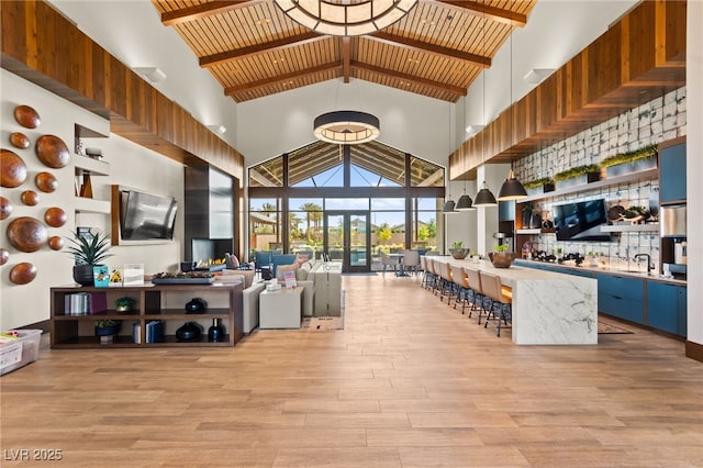 living room featuring light wood-type flooring, beam ceiling, and high vaulted ceiling