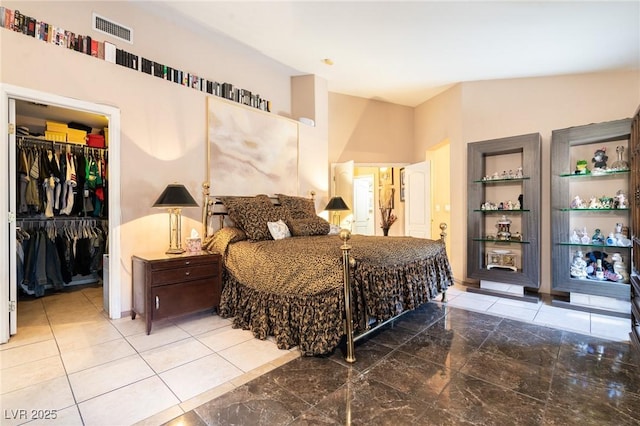 tiled bedroom with a walk in closet, a closet, and visible vents