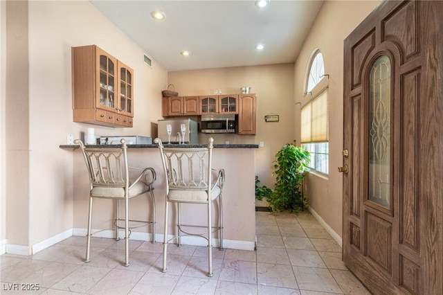 kitchen featuring visible vents, a healthy amount of sunlight, glass insert cabinets, and stainless steel microwave