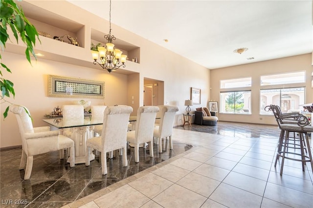 dining area with a towering ceiling, a notable chandelier, and baseboards