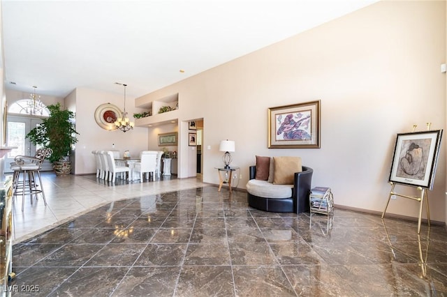interior space featuring baseboards, a towering ceiling, an inviting chandelier, and marble finish floor