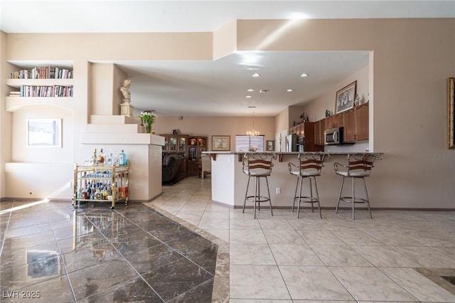 kitchen featuring a peninsula, stainless steel microwave, a breakfast bar, decorative light fixtures, and refrigerator