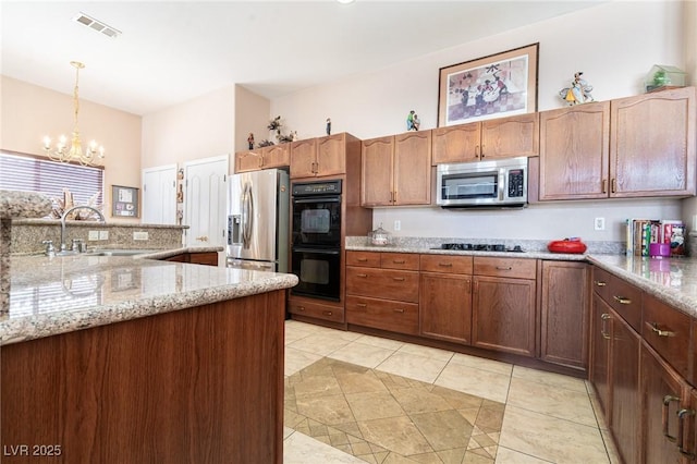 kitchen featuring an inviting chandelier, a sink, black appliances, visible vents, and decorative light fixtures