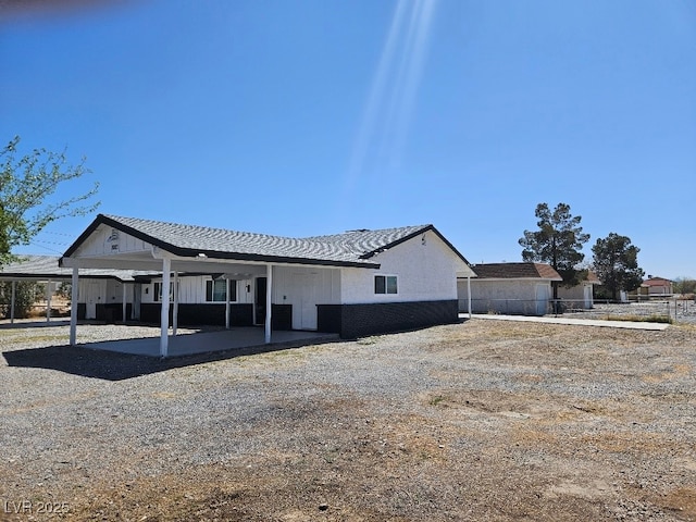 view of front facade featuring board and batten siding, fence, and a carport