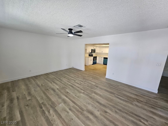 empty room with visible vents, wood finished floors, baseboards, ceiling fan, and a textured ceiling