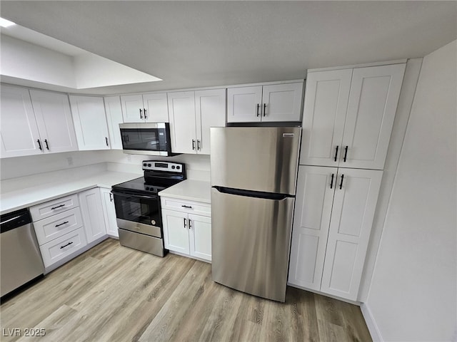 kitchen with light countertops, appliances with stainless steel finishes, white cabinets, and light wood-type flooring