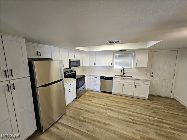 kitchen featuring white cabinets, a sink, a textured ceiling, stainless steel appliances, and visible vents