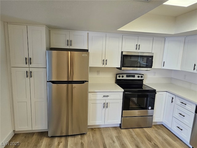 kitchen with light countertops, stainless steel appliances, white cabinetry, and light wood-style floors