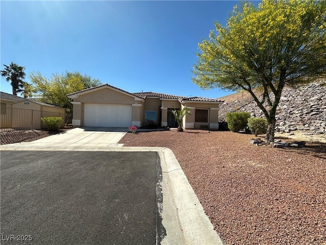view of front of home with a tile roof, concrete driveway, fence, an attached garage, and stucco siding