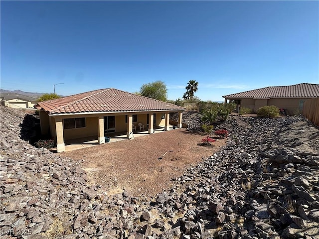 back of property featuring a patio area, a tile roof, and stucco siding
