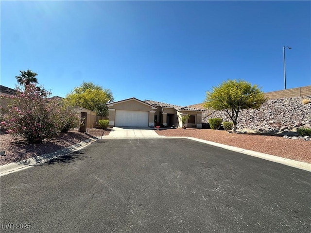 ranch-style home featuring an attached garage, a tile roof, concrete driveway, and stucco siding