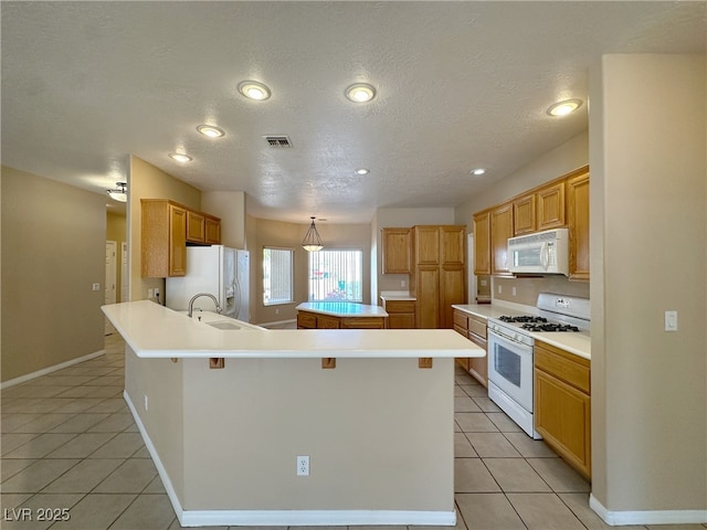 kitchen featuring a center island, light tile patterned floors, a sink, and white appliances