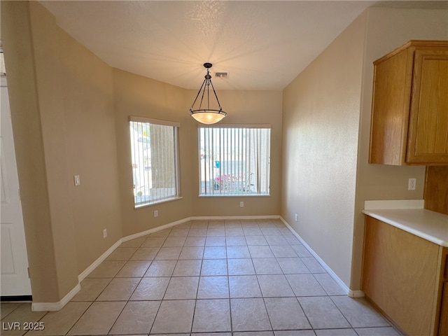 unfurnished dining area with baseboards, visible vents, and light tile patterned floors