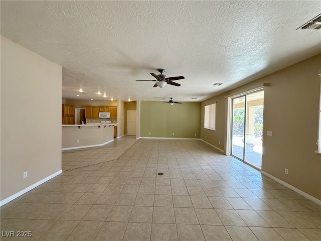 unfurnished living room featuring a textured ceiling, light tile patterned floors, ceiling fan, baseboards, and visible vents