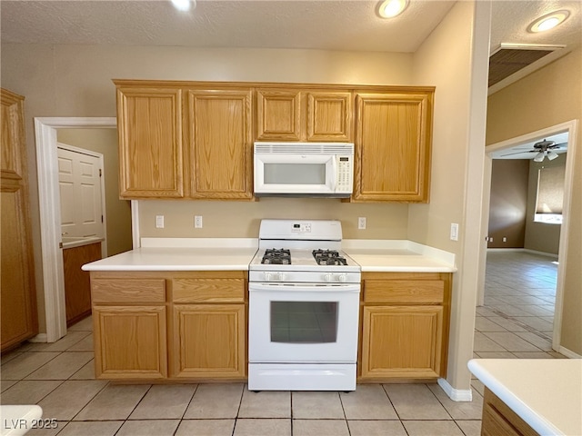 kitchen featuring a textured ceiling, white appliances, light tile patterned floors, ceiling fan, and light countertops
