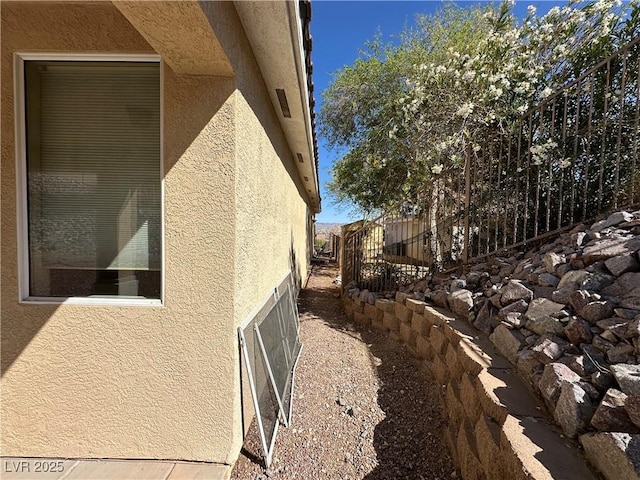 view of side of property featuring stucco siding and fence