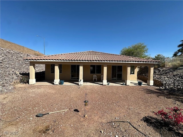 rear view of house with a patio area, a tiled roof, and stucco siding
