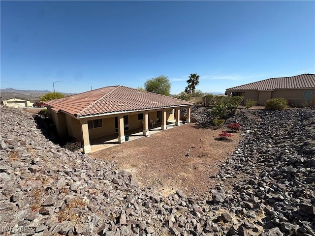 rear view of house featuring a patio, a tiled roof, and stucco siding