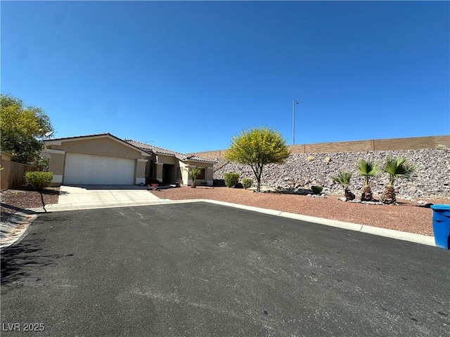 ranch-style house with stucco siding, an attached garage, driveway, and a tile roof