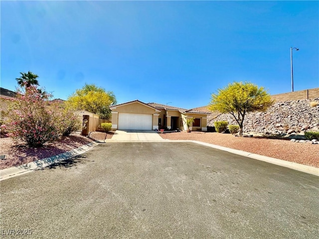 ranch-style house featuring a tiled roof, an attached garage, concrete driveway, and stucco siding