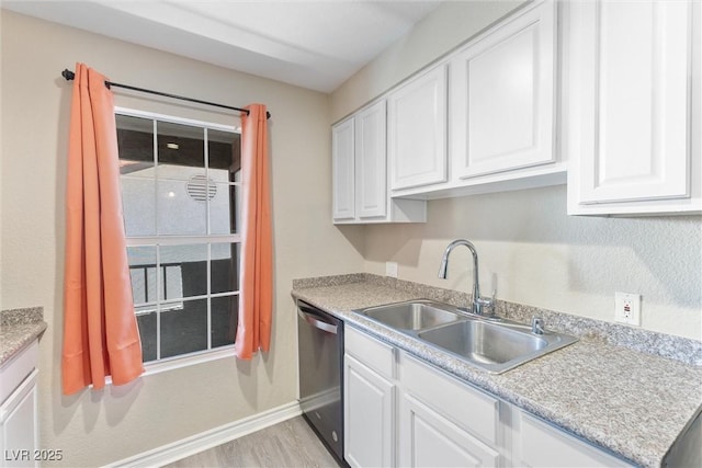 kitchen featuring white cabinets, stainless steel dishwasher, a sink, and light wood-style floors