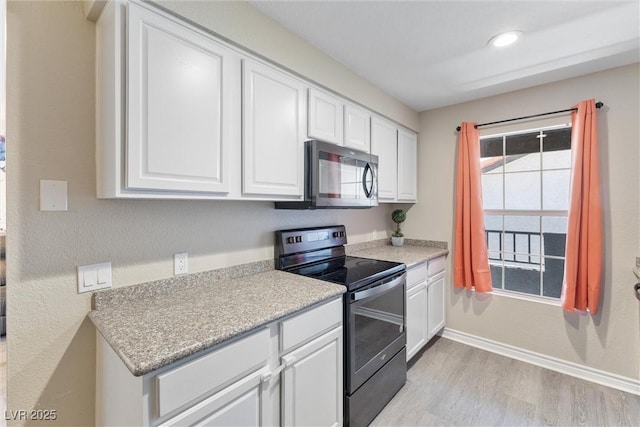 kitchen with range with electric cooktop, light countertops, stainless steel microwave, light wood-type flooring, and white cabinetry
