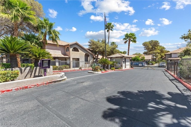 view of road featuring a gated entry, curbs, a gate, and a residential view