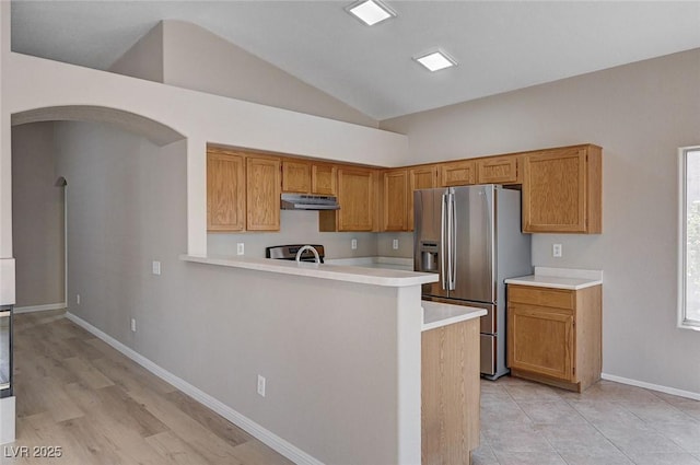 8028 Hurricane Cove Ct, Las Vegas, NV 89129 - kitchen featuring arched walkways, vaulted ceiling, stainless steel fridge with ice dispenser, light countertops, and under cabinet range hood